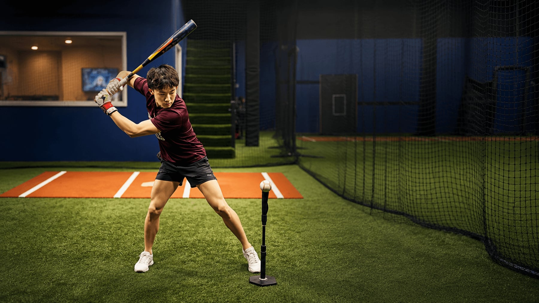 Cooper Won mid-swing inside an indoor batting cage